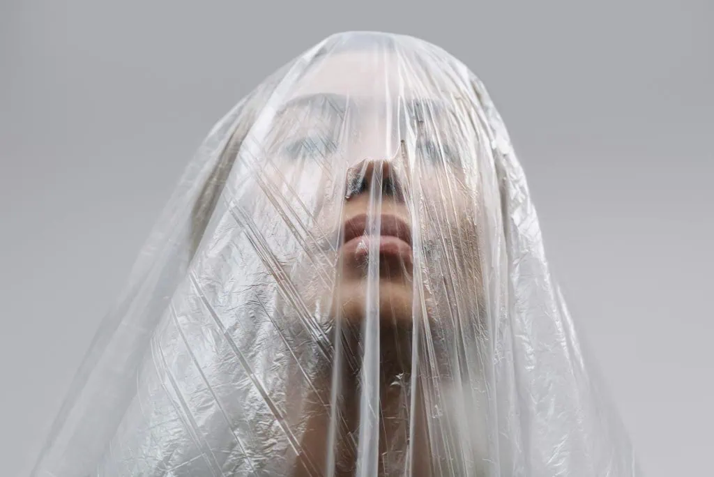 A person sits curled up in a dark, confined space with a distressed expression, visually representing the feeling of being trapped by overwhelming emotions or mental health struggles.
