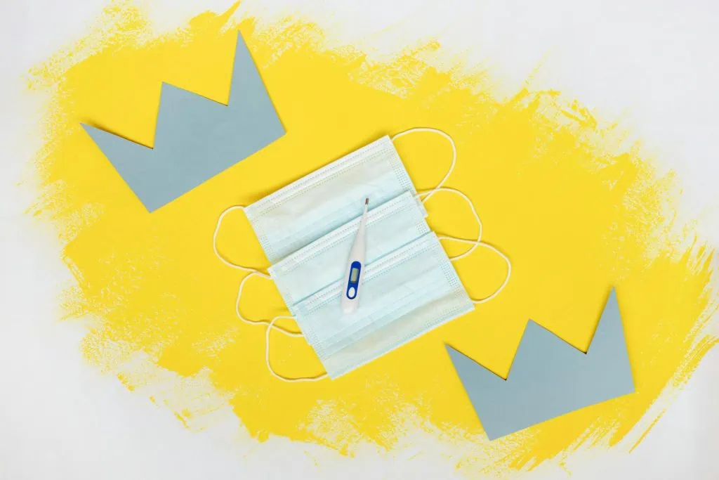 Medical masks and a thermometer on a yellow background, symbolizing health risks.