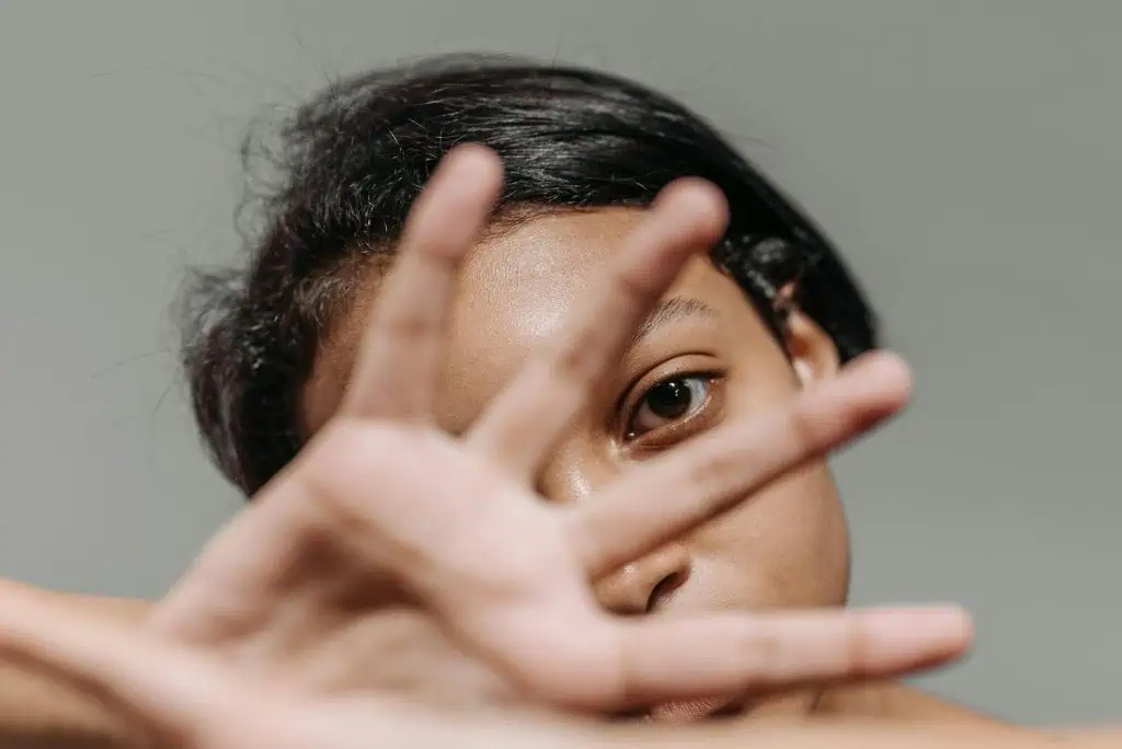 Close-up of a woman partially covering her face with her hand, symbolizing fear, anxiety, or emotional withdrawal.