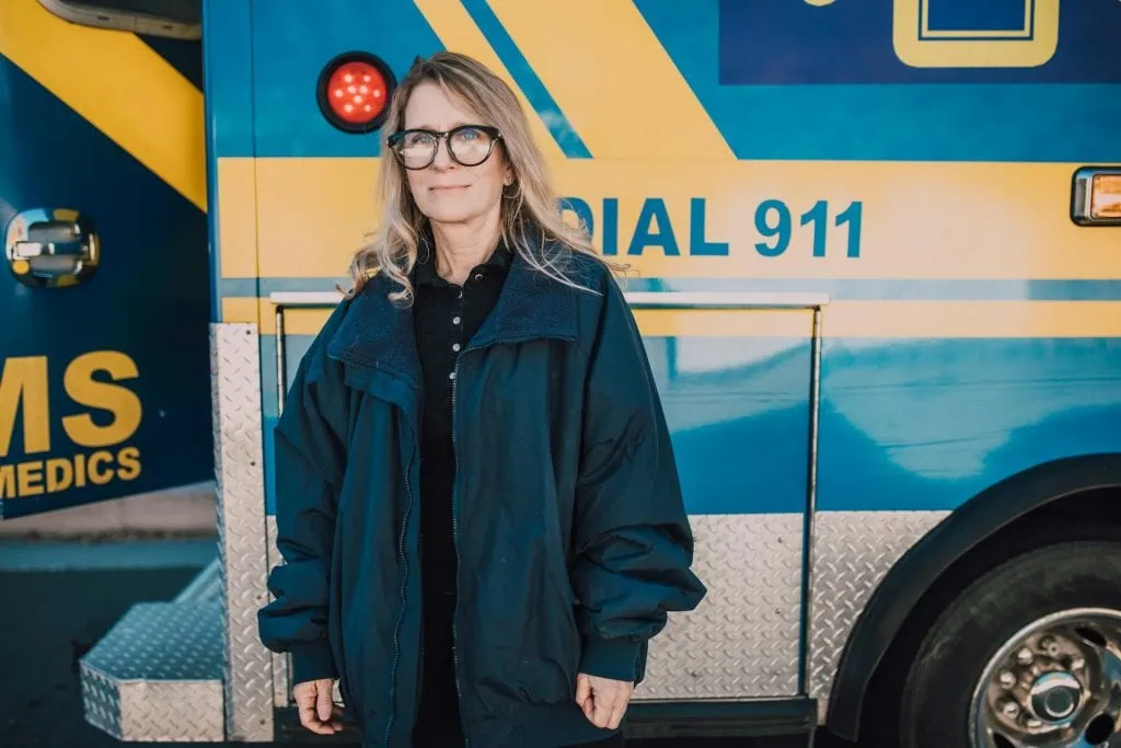 Female paramedic standing confidently beside an ambulance, representing women in male-dominated emergency services