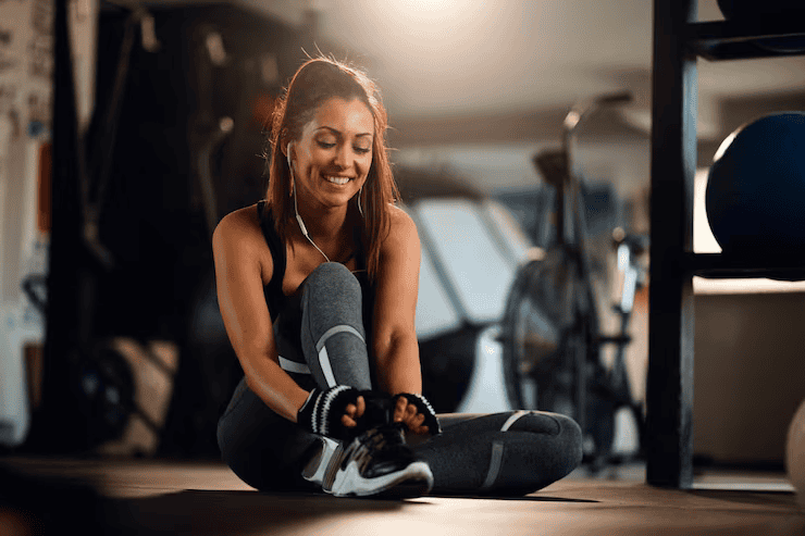 Young happy sportswoman getting ready workout tying shoelace fitness center